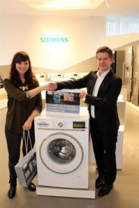 Kristin Katzer, eine der drei Gewinnerinnen des Siemens iSensoric-Wettbewerbs, nimmt ihre neue iSensoric-Waschmaschie von Brandmarketing Manager MArkus Ettenauer entgegen. 