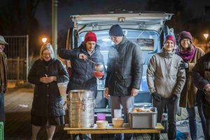Caritas Wien-Generalsekretär Klaus Schwertner und Drei CEO Jan Trionow (2.u.3.v.l.) gemeinsam mit Canisibus-Freiwilligen beim Austeilen warmer Mahlzeiten in der Kälte.